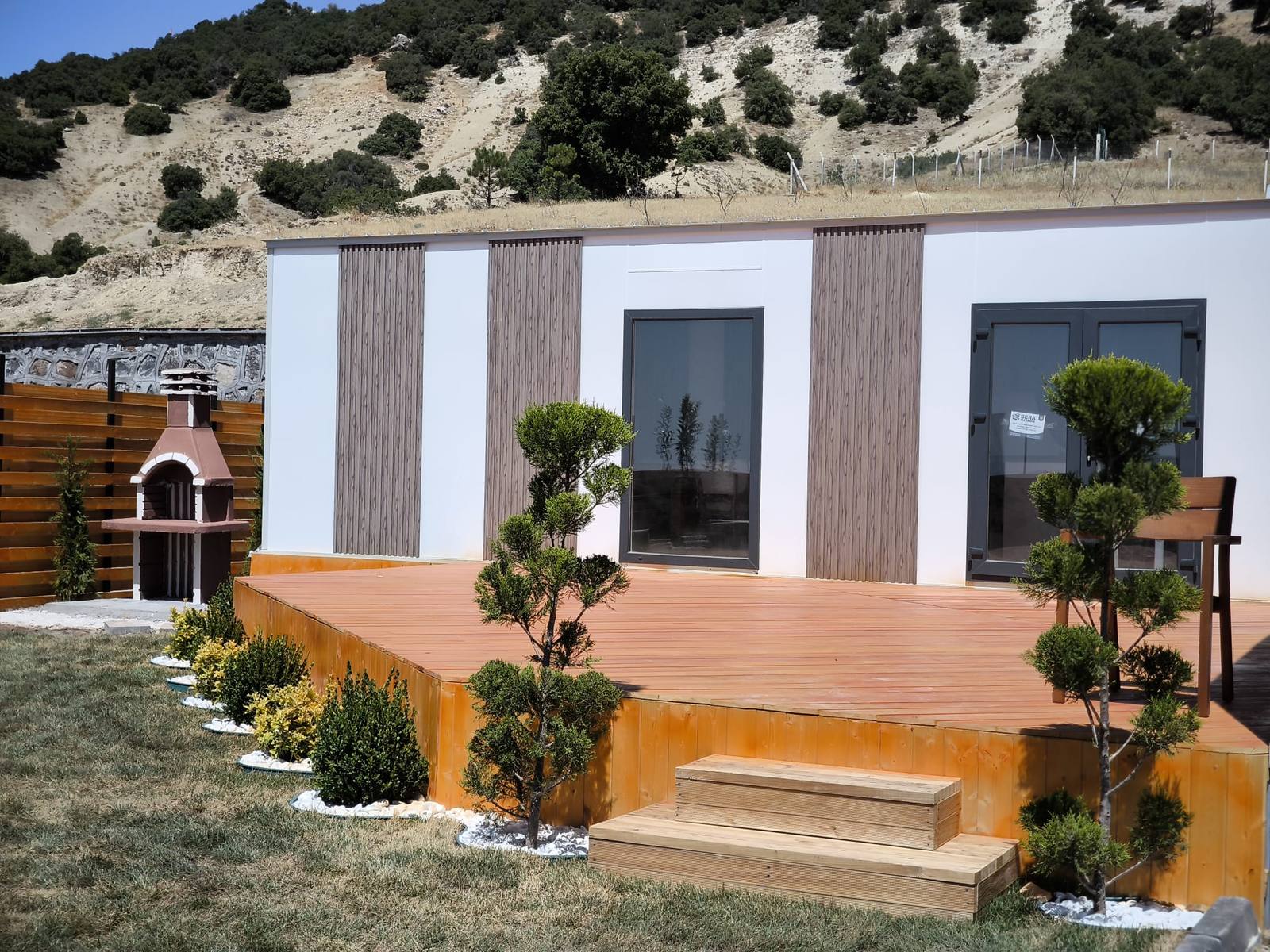 Ahşap teras üzerine kurulu tuğla barbekü, modern prefab ev