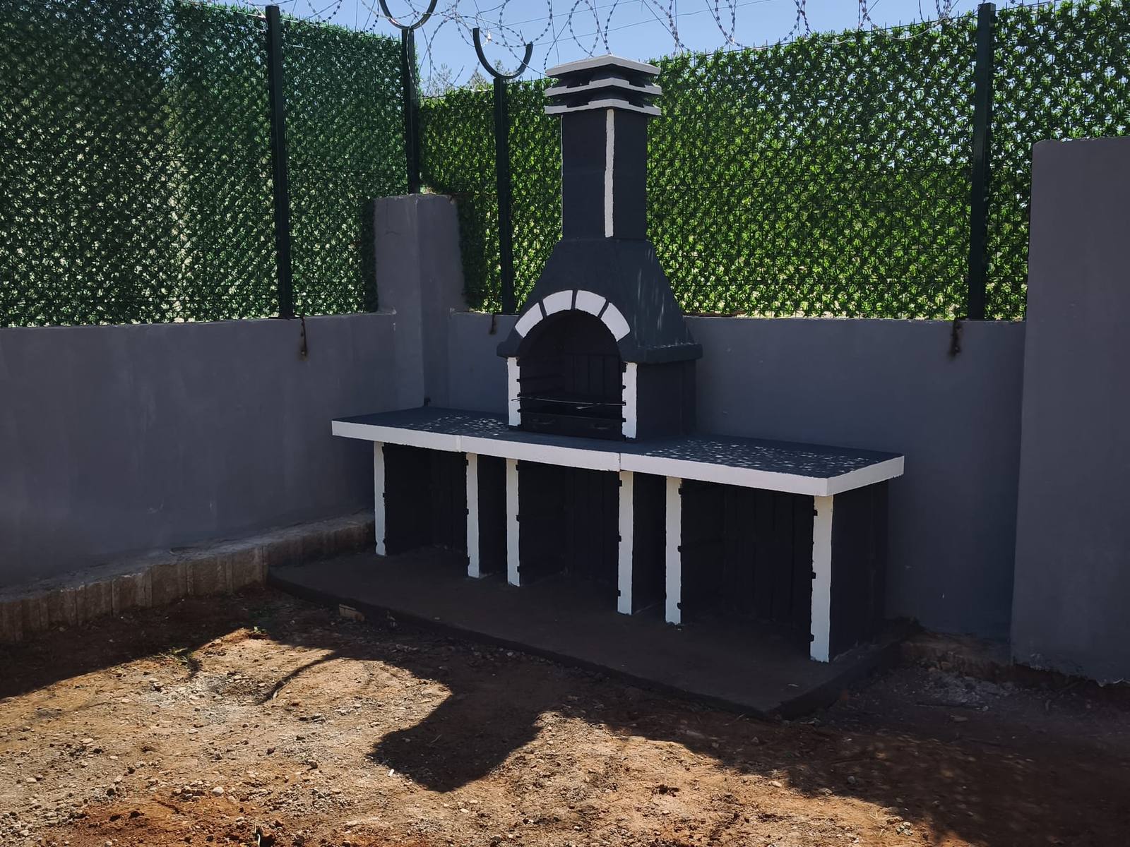Çim çit ile çevrili bahçede barbekü, altın saat ışığı